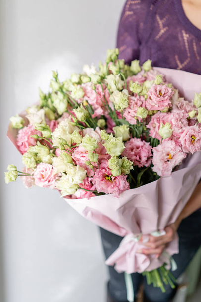szép tavaszi csokor. Fiatal girl gazdaság egy virág elrendezése, lisianthus rózsaszín színben - Fotó, kép