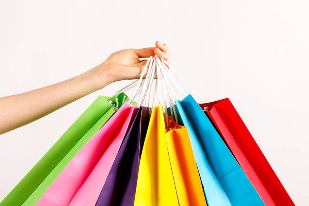 Cropped shot of female hand holding bunch of different colorful blank shopping bags over isolated white background. Many packets with in woman's arms. Black friday sale concept. Copy space, close up. - Valokuva, kuva