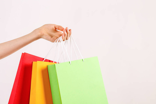 Cropped shot of female hand holding bunch of different colorful blank shopping bags over isolated white background. Many packets with in woman's arms. Black friday sale concept. Copy space, close up. - Fotoğraf, Görsel