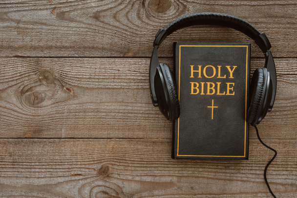 Ansicht der Heiligen Bibel mit Kopfhörer auf Holzoberfläche - Foto, Bild