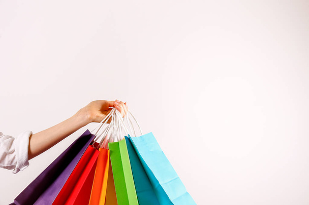 Cropped shot of female hand holding bunch of different colorful blank shopping bags over isolated white background. Many packets with in woman's arms. Black friday sale concept. Copy space, close up. - Fotoğraf, Görsel