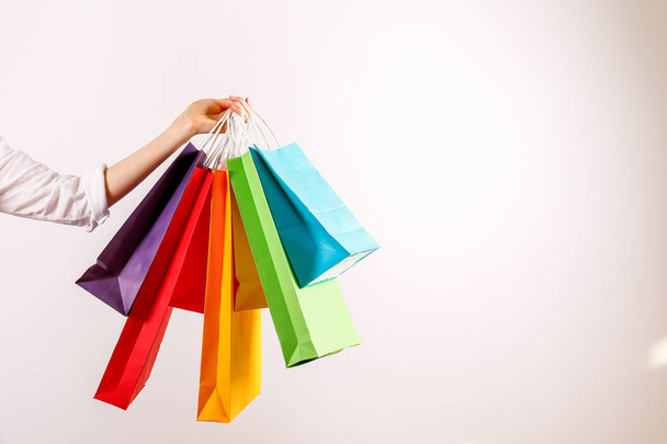 Cropped shot of female hand holding bunch of different colorful blank shopping bags over isolated white background. Many packets with in woman's arms. Black friday sale concept. Copy space, close up. - Foto, Imagem