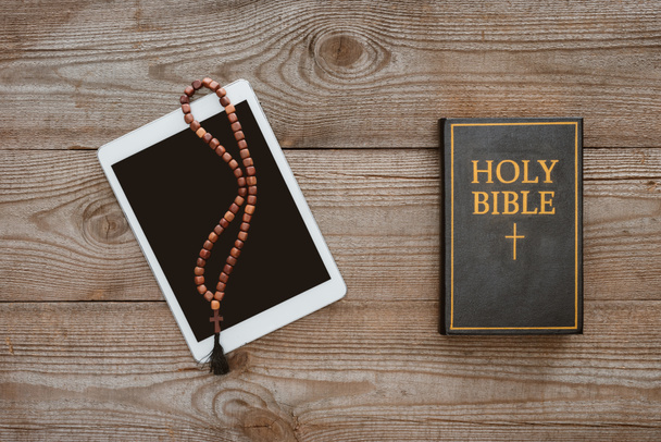 tablet ile boncuk ve İncil'de ahşap masanın üzerinde yatan bir üstten görünüm - Fotoğraf, Görsel