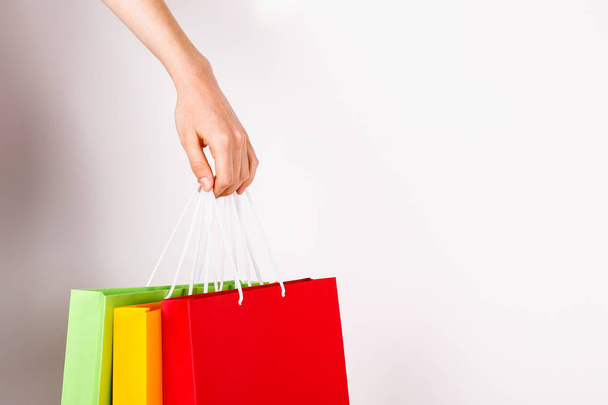 Cropped shot of female hand holding bunch of different colorful blank shopping bags over isolated white background. Many packets with in woman's arms. Black friday sale concept. Copy space, close up. - Φωτογραφία, εικόνα