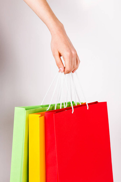 Cropped shot of female hand holding bunch of different colorful blank shopping bags over isolated white background. Many packets with in woman's arms. Black friday sale concept. Copy space, close up. - Photo, Image