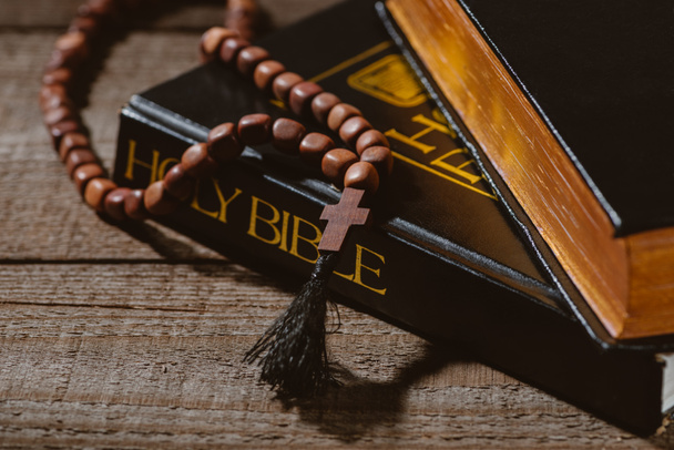 Nahaufnahme heiliger Bibeln mit Perlen auf Holztisch - Foto, Bild