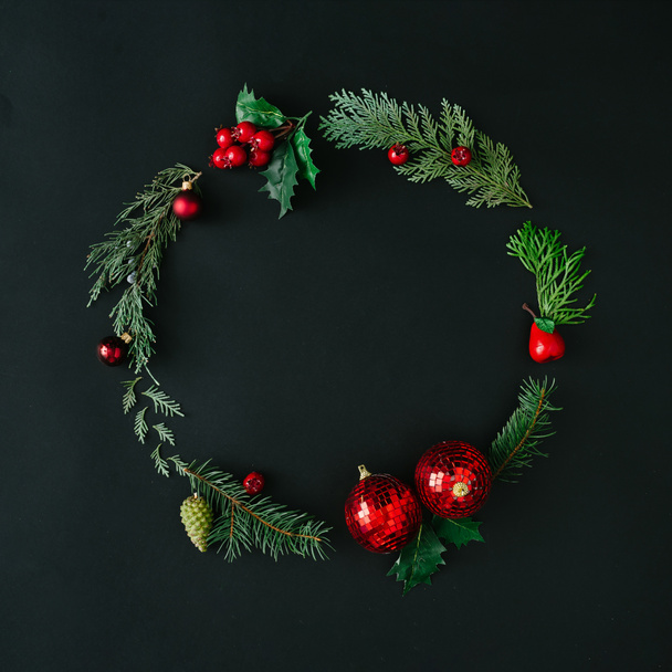 Kreatív karácsonyi koszorút készült természetes téli örökzöld fa ágak, és a piros bogyós gyümölcsök a baubles. Lapos feküdt. Természet koncepció. - Fotó, kép