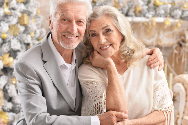 Retrato de abrazar a pareja mayor con decoraciones borrosas de Navidad en el fondo
 - Foto, imagen