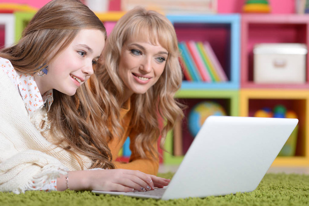 Young woman with  girl using laptop at home on floor - Photo, Image