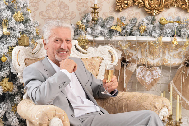 Portrait of confident senior businessman sitting in chair in room decorated to Christmas holiday - Fotoğraf, Görsel