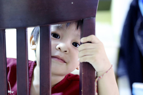 kid cute boy looking behind the chair. - Fotografie, Obrázek
