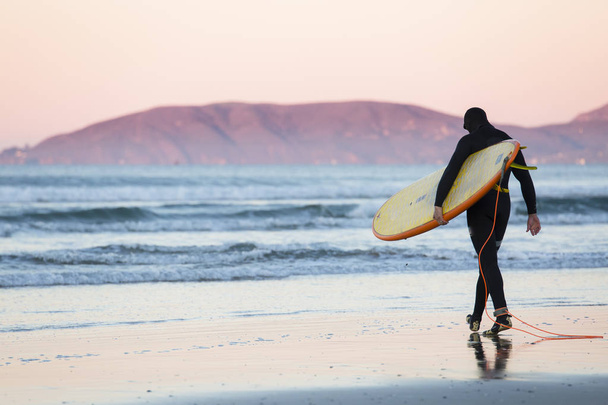 Surfer z pokładzie chodzenie w kierunku wody w zimny zimowy poranek w Kalifornii - Zdjęcie, obraz