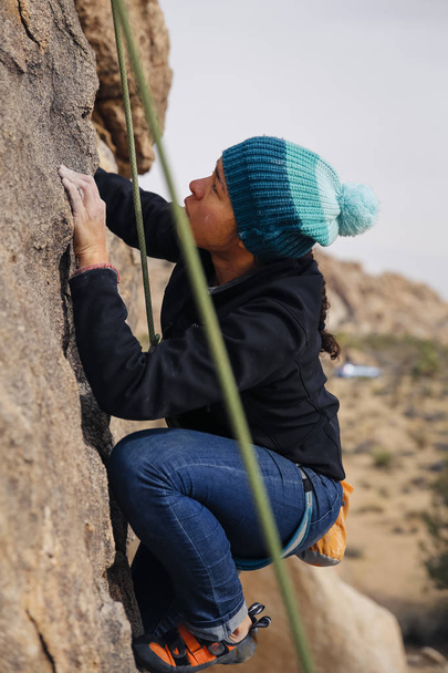 Gemengde race vrouw rots beklimmingen in de woestijn - Foto, afbeelding