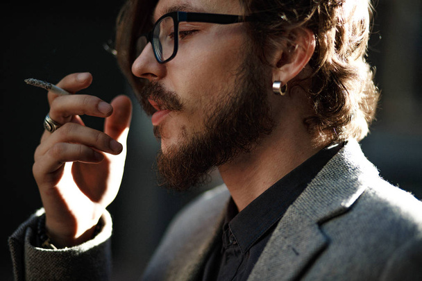 A man with long hair smokes outside - Foto, Bild