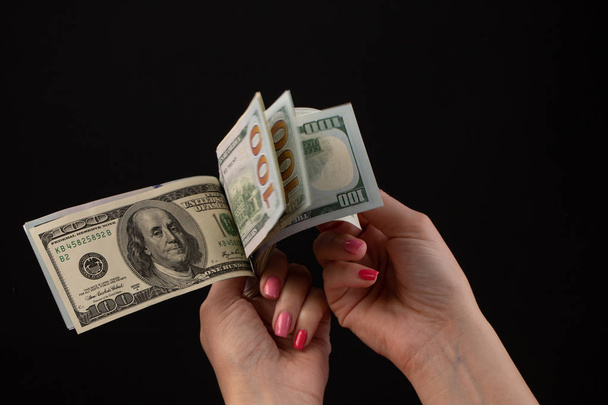 Hand giving money, United States Dollars or USD. Hands holding Banknotes. Hands holding a dollar 100 bill on black background - Photo, Image