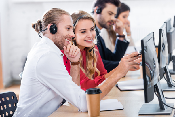 foco seletivo de operadores de call center sorridentes trabalhando no local de trabalho com café para ir no escritório
 - Foto, Imagem