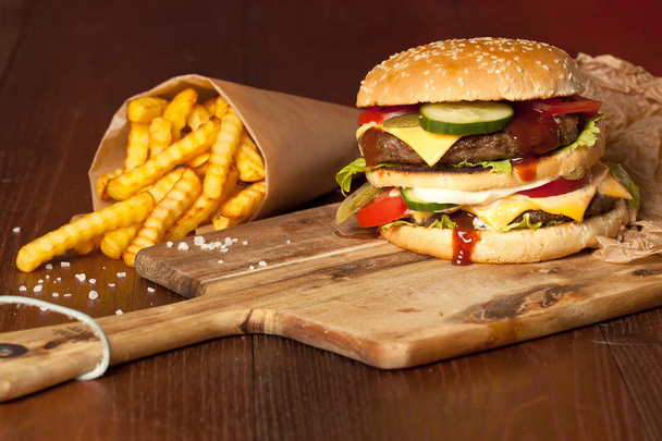 Fast food hamburger and french fries on a wooden Background - Photo, image