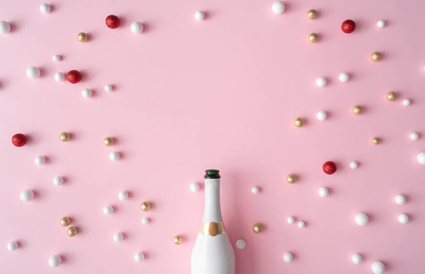 Carte de voeux Nouvel An avec bouteille de champagne et boules de décoration pailletées sur fond rose. Style minimal. Composition de la couche plane
. - Photo, image