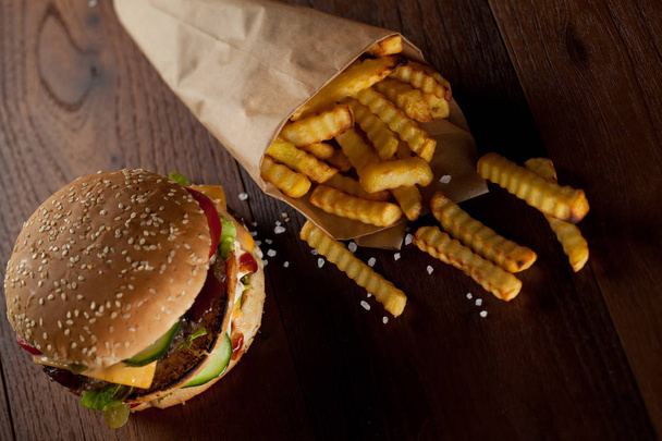 Fast-Food-Hamburger und Pommes auf einem hölzernen Hintergrund - Foto, Bild