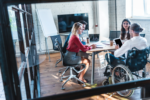 νέοι με αναπηρία επιχειρηματία στην αναπηρική καρέκλα εργασίας με τους συναδέλφους στο γραφείο    - Φωτογραφία, εικόνα