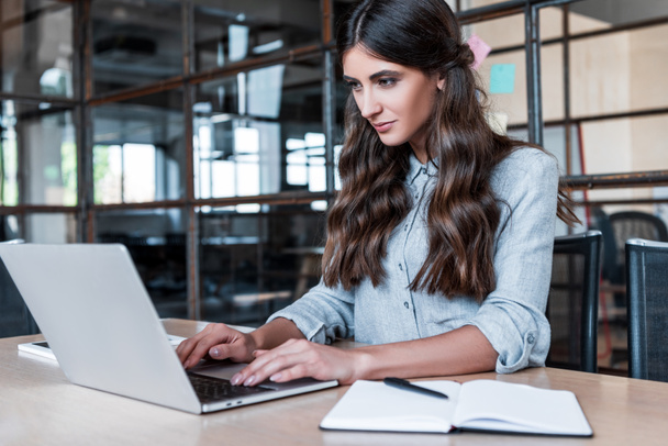 gyönyörű fiatal üzletasszony használ laptop a munkahelyen - Fotó, kép