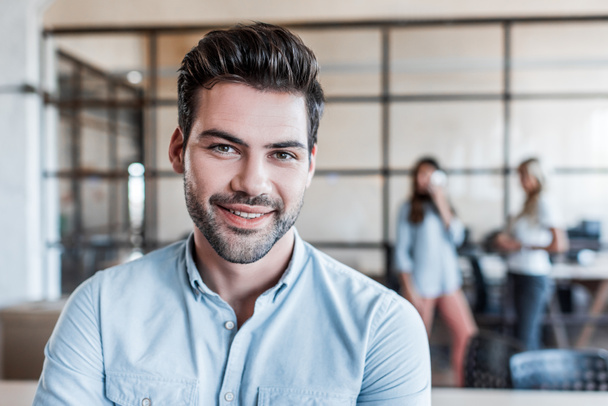 portrait of handsome young businessman smiling at camera in office - Foto, Bild