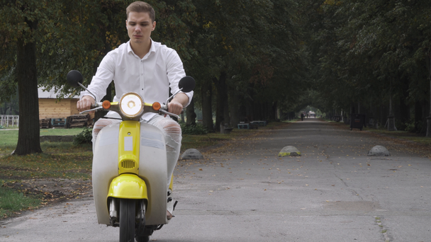 Smiling guy riding a scooter - Záběry, video