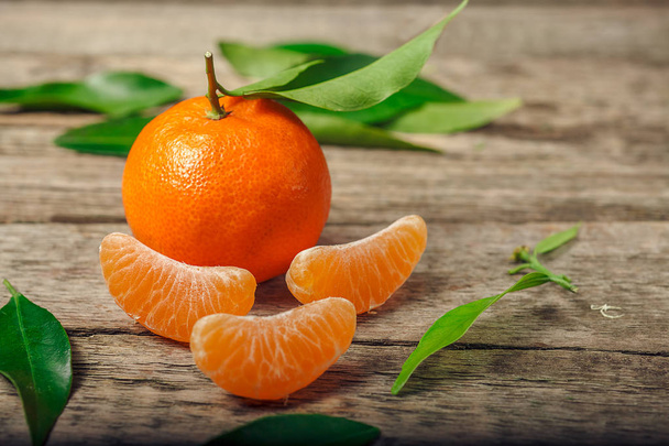Mandarinky (klementinky, pomeranče, citrusové plody) se zelenými listy dřevěné pozadí s kopie spac - Fotografie, Obrázek