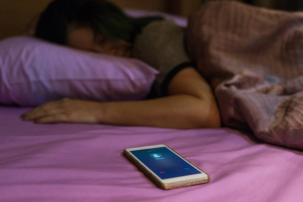 Dormindo mulher asiática e telefone celular com chamada de escritório na tela
 - Foto, Imagem