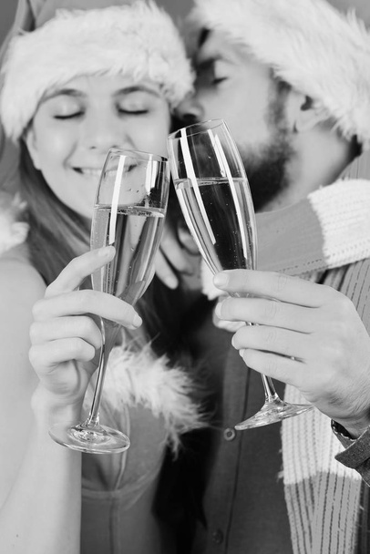 Mister and Missis Claus hold glasses of champagne cuddling - Foto, imagen