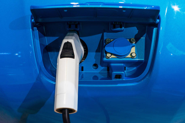 Bocal de tomada de carregador elétrico em um carro azul
 - Foto, Imagem