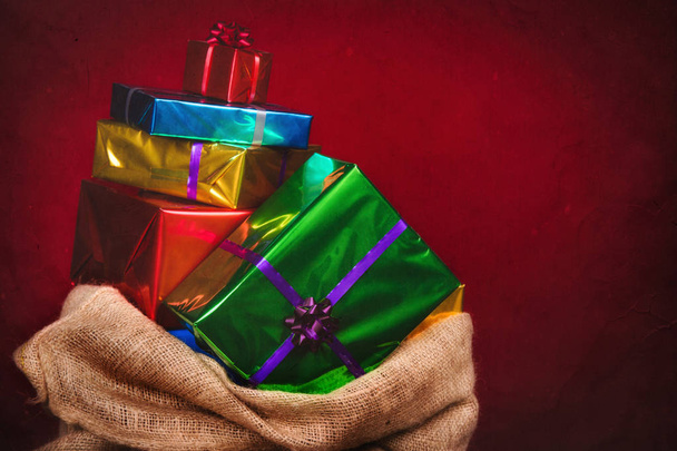 Мешок Sinterklaas с подарками .Burlap мешок на красном фоне. Винтажное редактирование
. - Фото, изображение