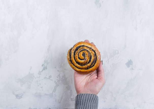Pastry food concept. Woman holding bun with poppy seeds. Top view, copy space - 写真・画像