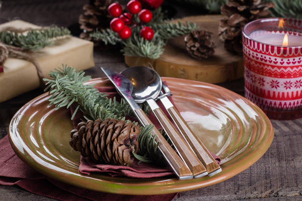 Christmas Setting Table. Dinner plate, silverware, fir tree, gift box, candle and festive decoration. Holiday Food Concept. - Photo, Image