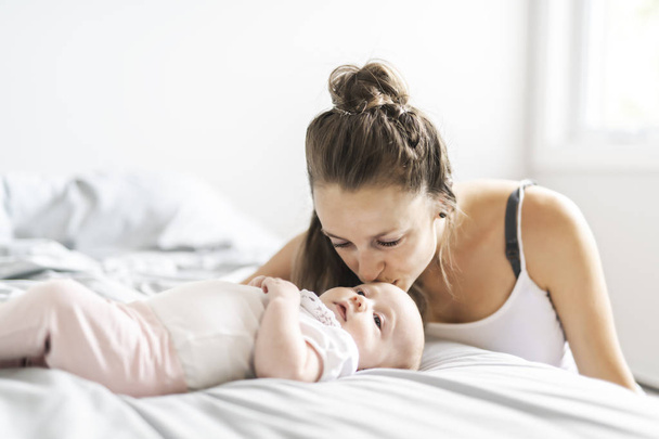 Portrait of a beautiful mother with her 2 month old baby in the bedroom - Photo, image