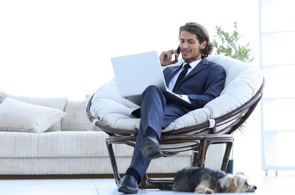 リビング ルームに座っているスマート フォンに話しているビジネス男性 - 写真・画像