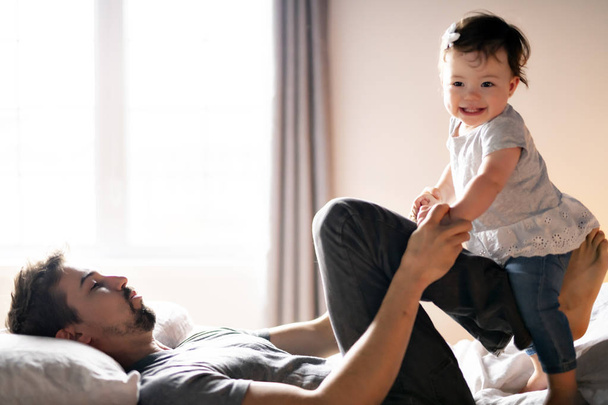 Young father with child girl on bed at home - Foto, Imagem
