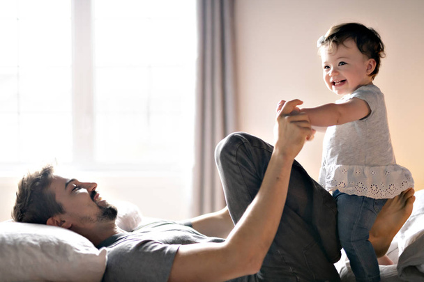 Young father with child girl on bed at home - Foto, imagen