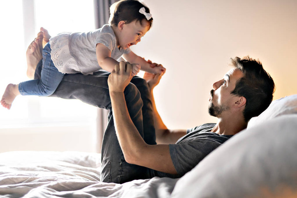 Young father with child girl on bed at home - Foto, immagini