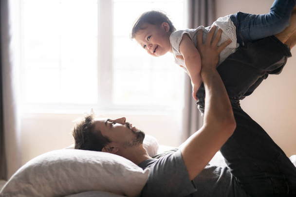 Young father with child girl on bed at home - Foto, Imagen