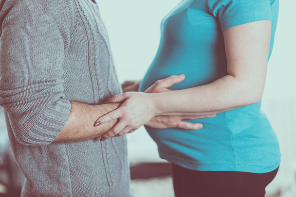 Беременная женщина и ее муж стоят, ожидая ребенка
 - Фото, изображение