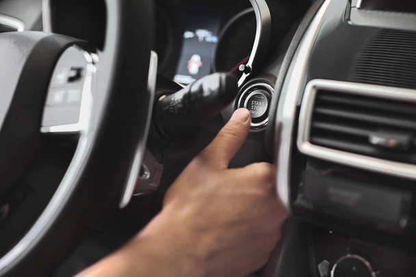 Finger pressing engine start button on car. The driver pushing on automatic start stop button. - Foto, afbeelding