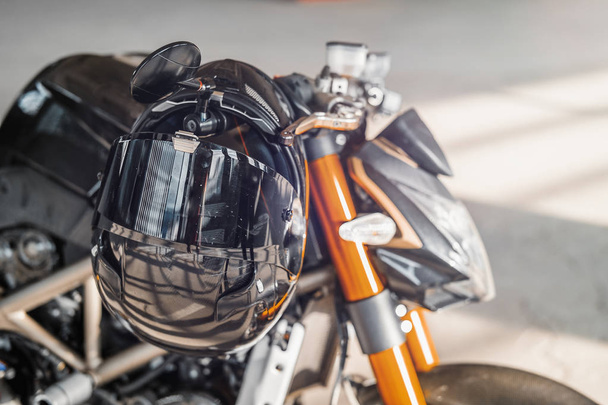 Close up of black glossy helmet at motorcycle. Urban background. - Photo, image