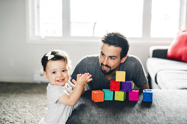 father and little daughter playing with toy blocks at home - Foto, afbeelding