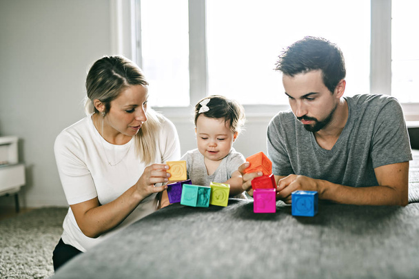 happy father, mother and little daughter playing with toy blocks at home - Foto, afbeelding