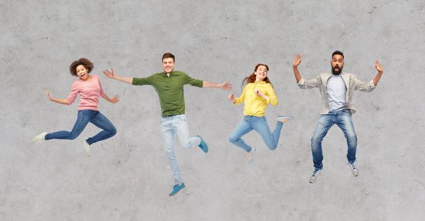 personas felices o amigos saltando en el aire sobre gris - Foto, Imagen