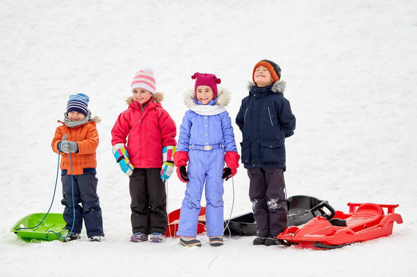 happy little kids with sleds in winter - Foto, imagen