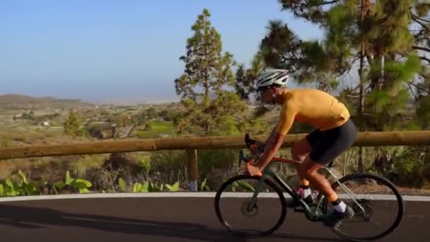 Geniş açı izleme uygun erkek atlet binicilik bisiklet kırsalında uzun düz yolda bir kadeh. Adam düz otoyol yolda Bisiklete binme. - Video, Çekim