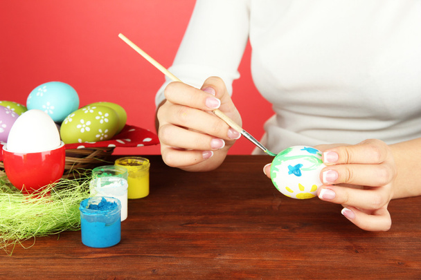Young woman painting Easter eggs, on color background - Fotografie, Obrázek