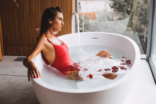 Vrouw zwemmen en ontspannen in een moderne badkuip - Foto, afbeelding